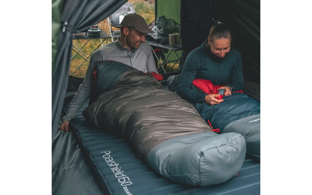 Een man in een slaapzak en een vrouw naast hem, beiden in een tent