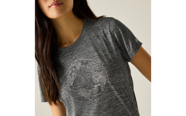 Buste d'une personne portant un gris t‑shirt chiné avec un motif circulaire floral centré, longs cheveux foncés, menton et lèvres visibles, fond clair
