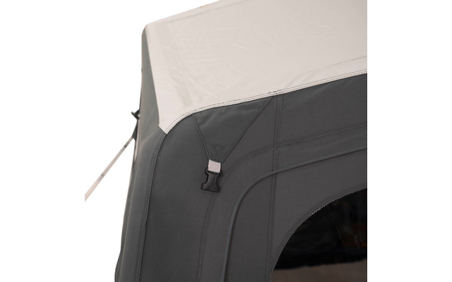 Eckansicht einer grauen Stoffstruktur mit weißer Dachplane, schwarzer Kunststoffschließe, sichtbaren Nähten und einem dunklen, abgerundeten Fenster