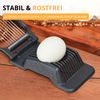 Trancheur d'œuf avec un œuf écalé sur une planche en bois; texte en arrière-plan 'STABIL & ROSTFREI' et étiquette jaune 'ALUMINIUM & EDELSTAHL FÜR LANGANHALTENDE QUALITÄT'