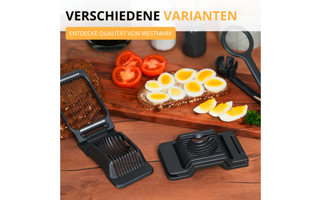 Deux tranche-œufs noirs sur une table en bois à côté d'œufs durs tranchés sur du pain, des tranches de tomate, une planche à découper et des ustensiles de cuisine