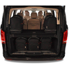 Coffre ouvert d'une camionnette noire avec cinq sacs à dos noirs (deux sur l'étagère supérieure, trois sur l'étagère inférieure), intérieur beige et plusieurs sièges avec appuie-têtes visibles