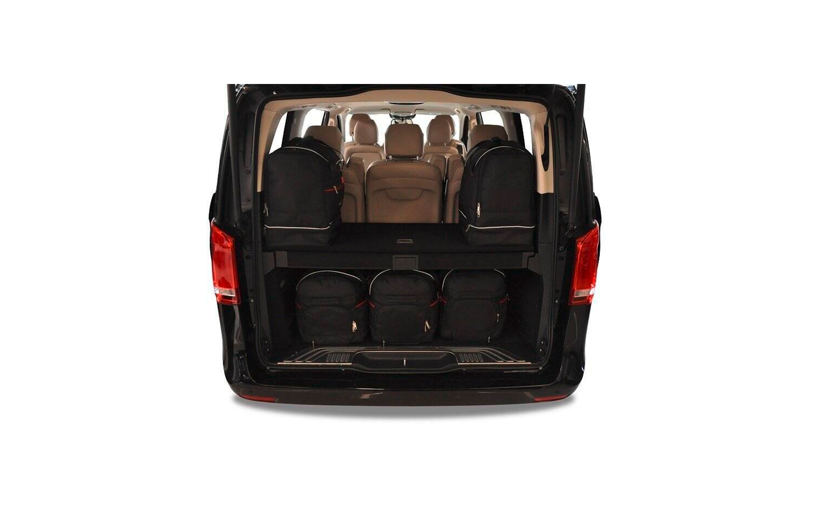 Coffre ouvert d'une camionnette noire avec cinq sacs à dos noirs (deux sur l'étagère supérieure, trois sur l'étagère inférieure), intérieur beige et plusieurs sièges avec appuie-têtes visibles