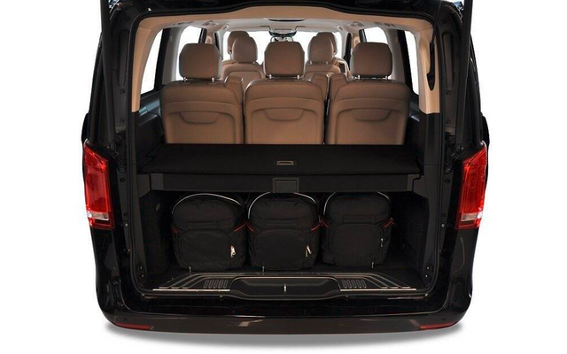 Arrière ouvert d'une camionnette noire avec trois sièges en cuir beige, une tablette de coffre et trois sacs à dos noirs dans le coffre
