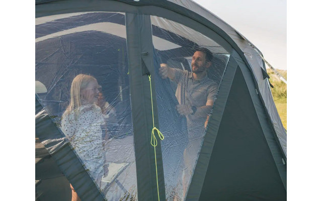 Zwei Menschen sitzen in einem Zelt auf einem Grasfeld bei sonnigem Wetter