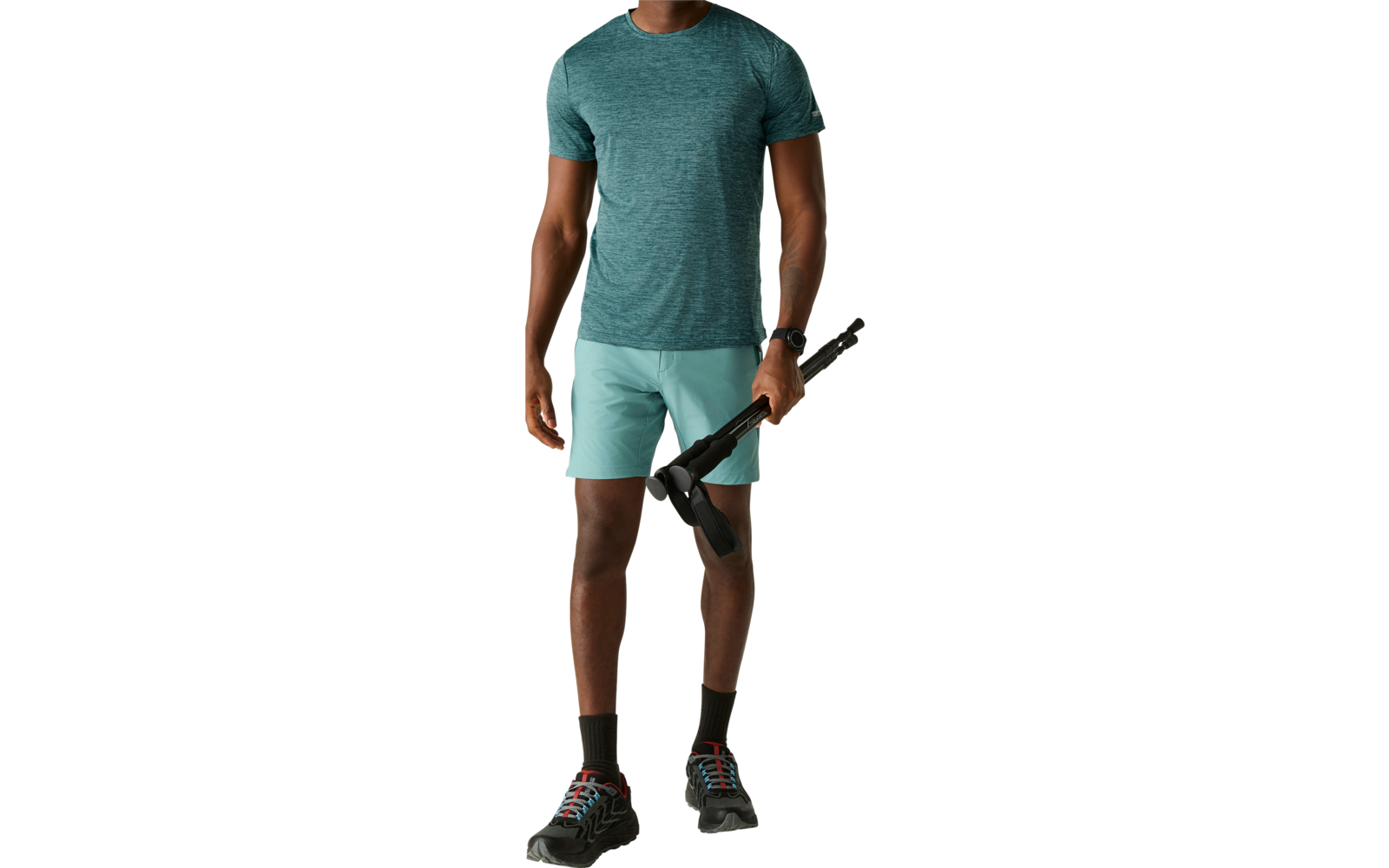 Ein Mann steht und blickt nach links, trägt ein blaugrünes kurzärmliges T-Shirt, helltürkisfarbene Shorts, schwarze Socken und schwarze Sportschuhe; in der rechten Hand hält er einen zusammengefalteten schwarzen Regenschirm. Heller einfarbiger Hinter