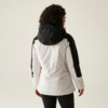 Vrouw met krullend haar die een witte jas met zwarte mouwen draagt, gefotografeerd van achteren