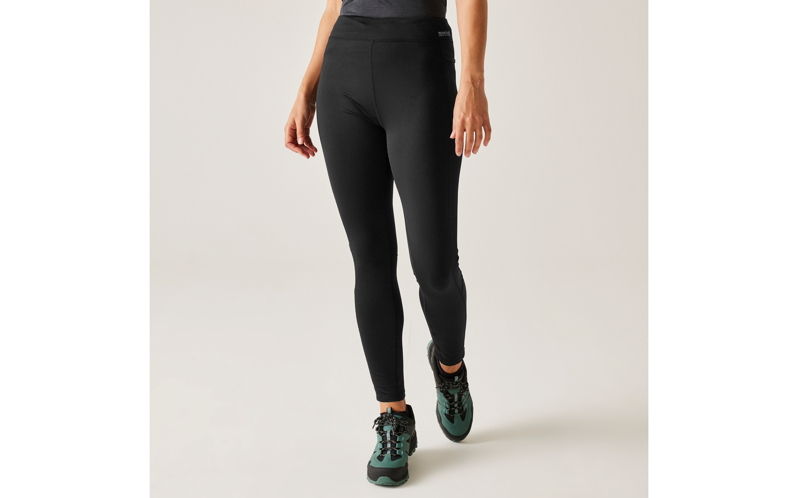 Frau trägt schwarze Leggings und schwarze Sportschuhe mit grünen Details