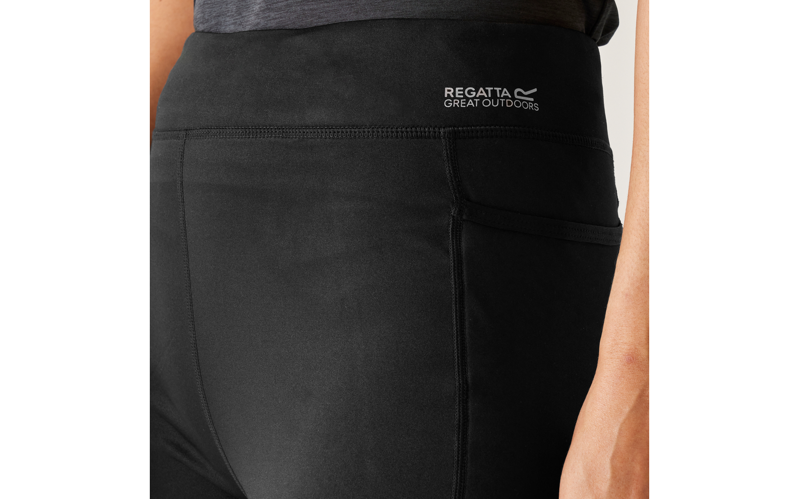 Région des hanches portant un legging noir, logo blanc 'Regatta Great Outdoors' sur la ceinture, poche latérale visible, main droite le long de la jambe
