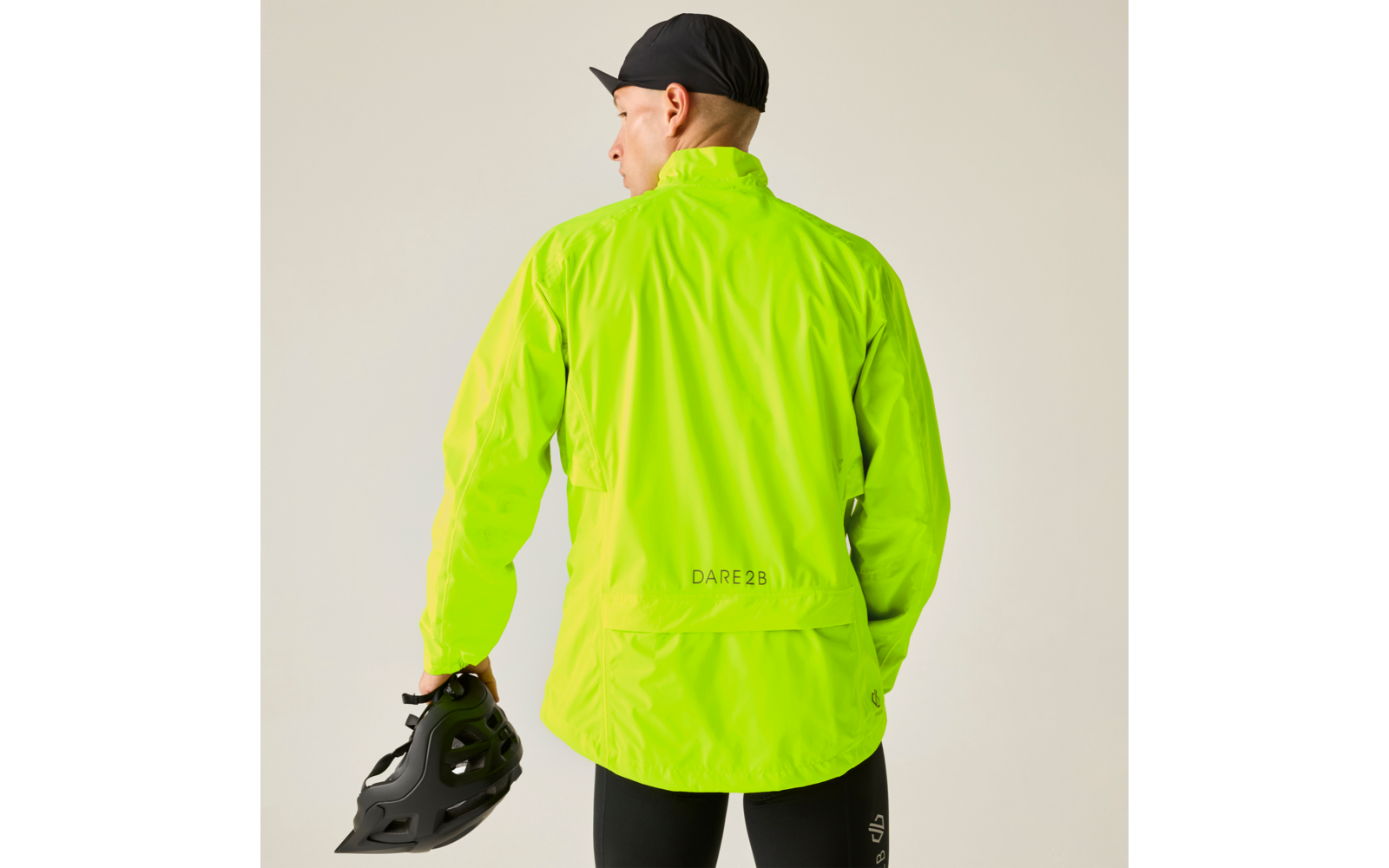 Person von hinten in neongrüner Jacke mit Aufschrift DARE 2B, schwarzer Kappe, hält einen schwarzen Helm in der rechten Hand