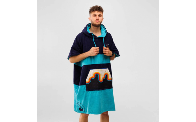 Ein Mann trägt einen bunten Kapuzenponcho mit Mustern in Blau, Türkis und Orange