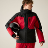 Person in roter und schwarzer Jacke und roten Hosen hält einen schwarz-weißen Helm, Blick nach rechts