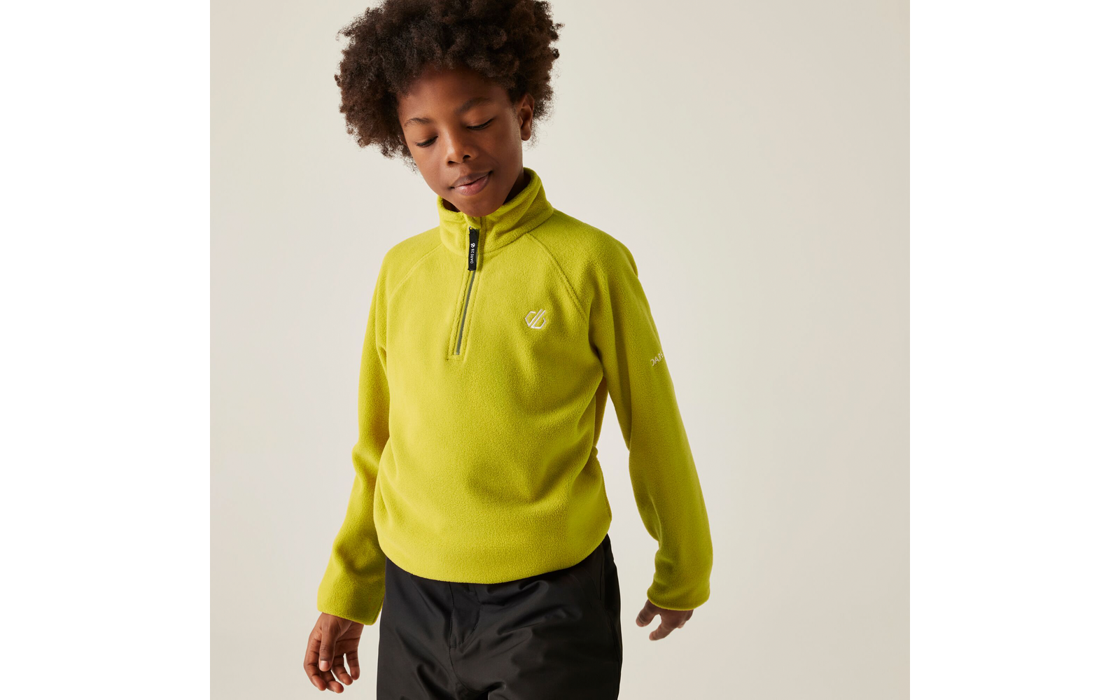 Junge mit gelbem Pullover und dunkler Hose schaut nach unten