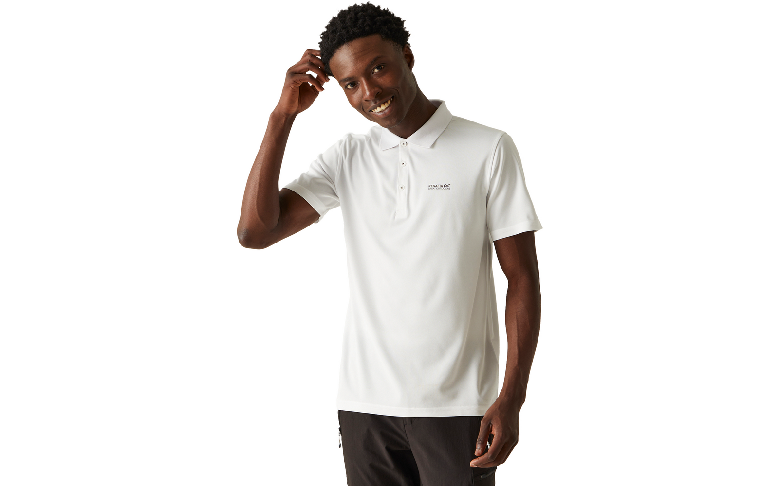 Mann in weißem Poloshirt mit kleinem Logo auf der Brust und dunkler Hose, berührt mit der rechten Hand sein Haar, lächelt, weißer Hintergrund