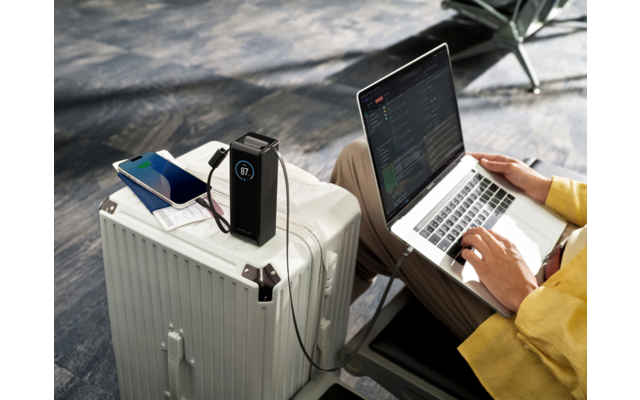 Offener Laptop auf einem weißen Koffer, daneben ein Smartphone, eine Person tippt auf der Tastatur