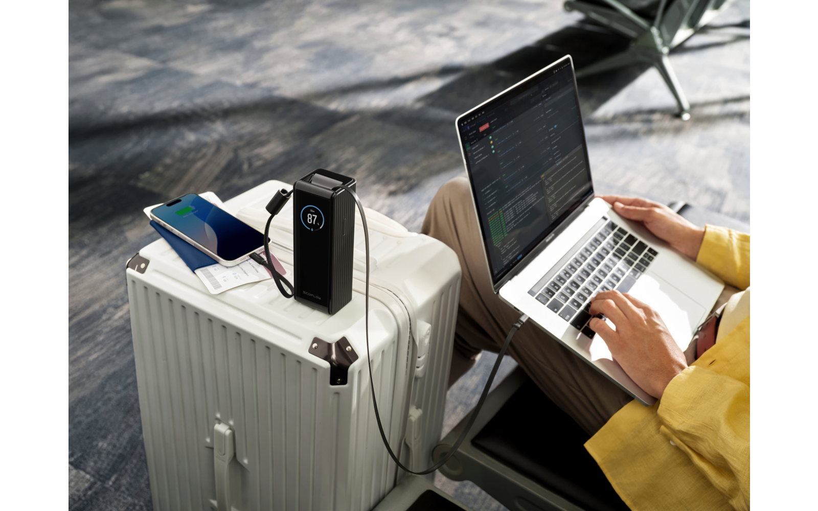 Offener Laptop auf einem weißen Koffer, daneben ein Smartphone, eine Person tippt auf der Tastatur