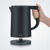 Bollitore elettrico nero su base, tenuto da una mano