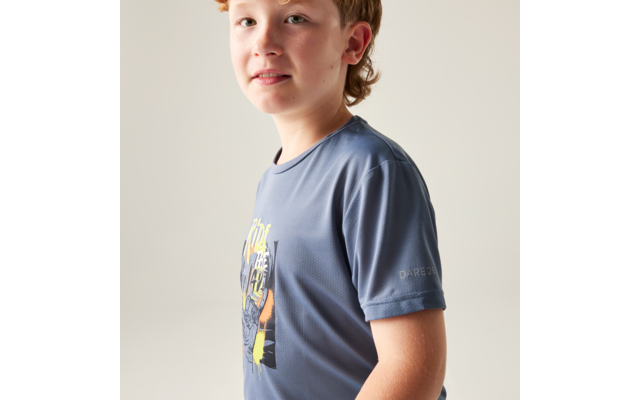 Halbkörperaufnahme eines Kindes in Dreiviertelansicht, trägt ein blaues T‑Shirt mit buntem Aufdruck vor hellem einfarbigem Hintergrund