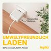 Weißes Ladegerät mit Kabel auf hellem Holztisch neben einem grünen Blatt