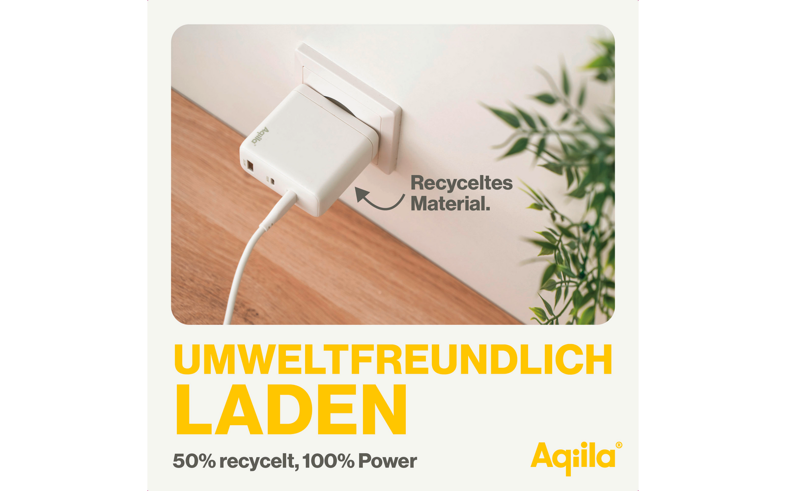Weißes Ladegerät mit Kabel auf hellem Holztisch neben einem grünen Blatt