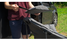 Person schiebt gepolsterte Sitzauflage auf klappbaren Kinderwagen