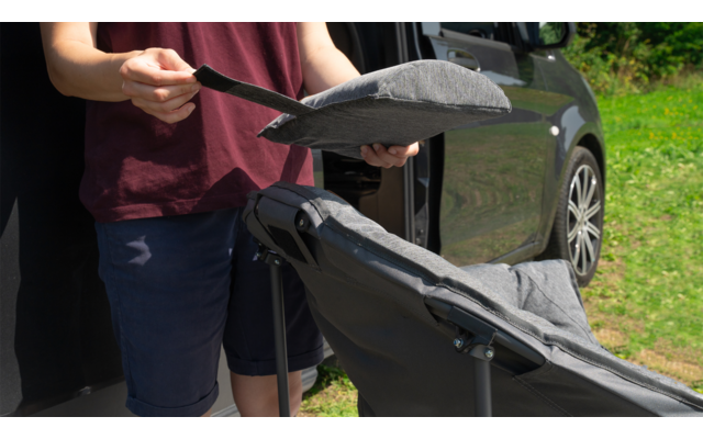 Person schiebt gepolsterte Sitzauflage auf klappbaren Kinderwagen