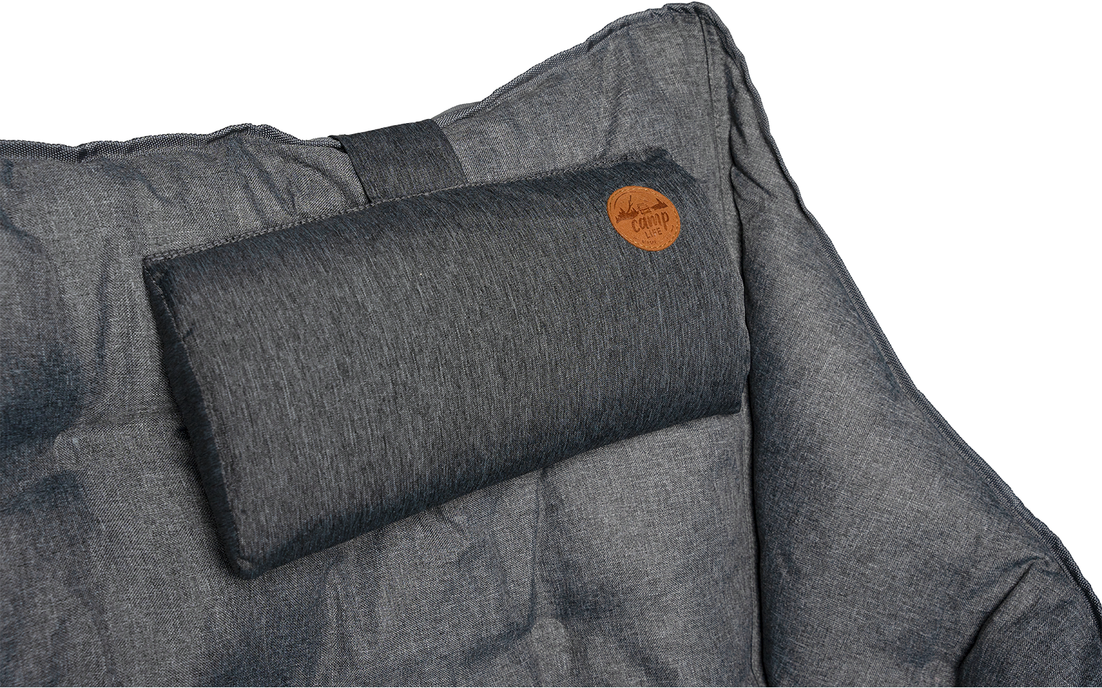 Gray quilted padded surface with a small rectangular cushion at the top edge and a round brown leather patch on the cushion