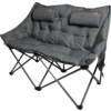 Two-seat dark gray padded folding bench on a black X-shaped metal frame; quilted surface; two cylindrical head cushions with brown round patches