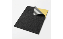 Donkergrijs rechthoekig vilten vel met bovenste rechterhoek teruggevouwen, waarbij een zilveren laag en een geel achtervlak zichtbaar zijn, op een witte achtergrond