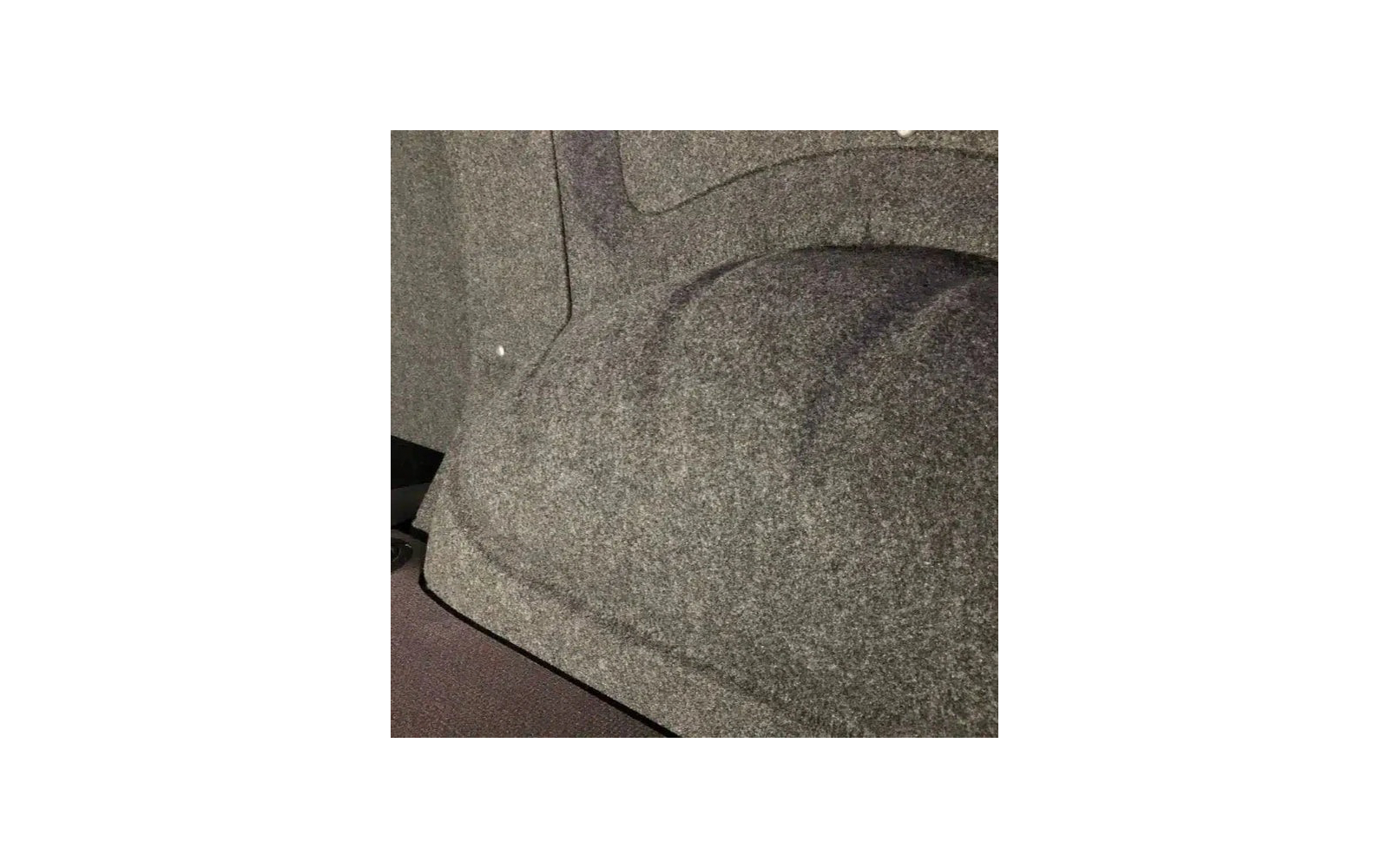 Grijze, gestructureerde vilt- of tapijtachtige oppervlakte met een afgerond verheven gedeelte en een zichtbare rand