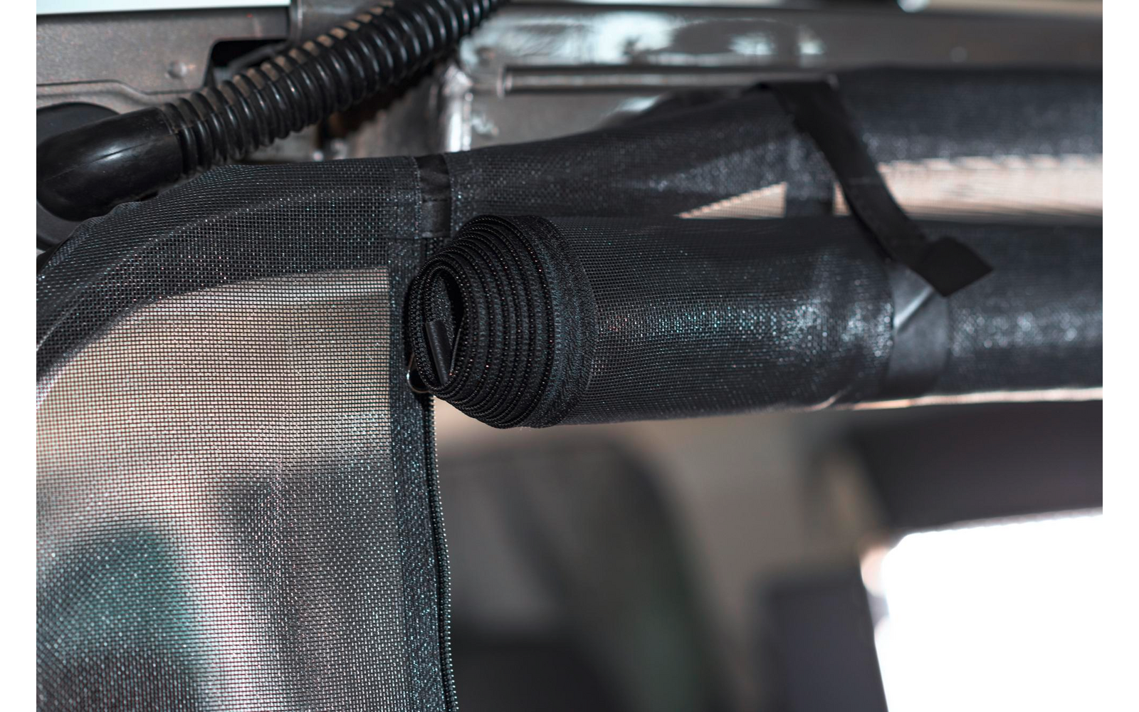 Nahaufnahme eines schwarzen Kunststoffrohrs, das mit Kabelbindern an einem Metallrahmen befestigt ist