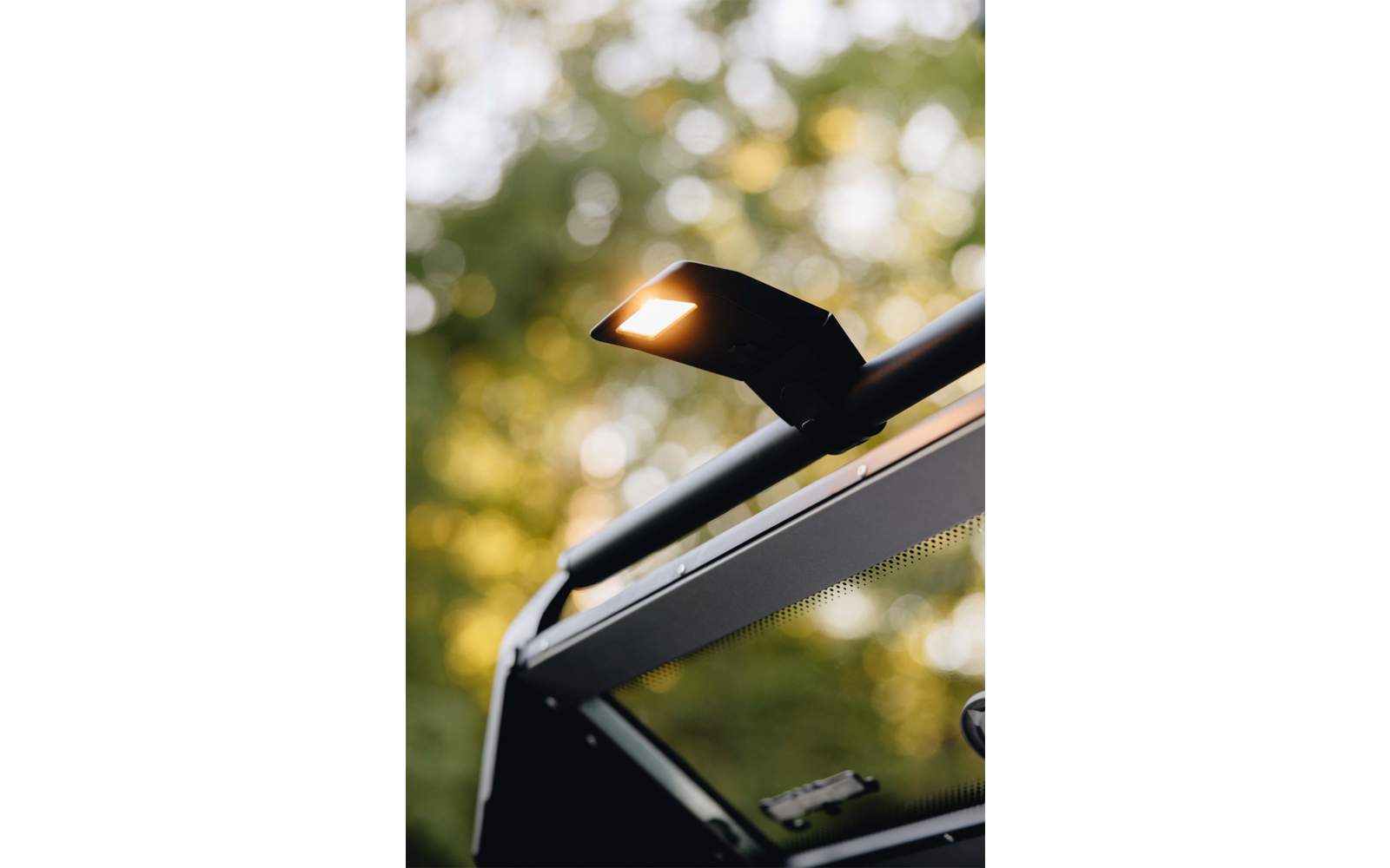 Beleuchtetes rechteckiges LED-Licht an einem dunklen Metallrahmen, unscharfer grüner Hintergrund