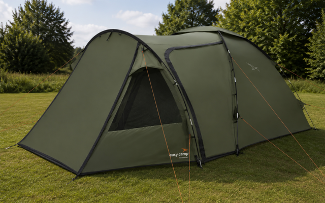 Green tunnel tent on grass, front entrance open showing a mesh window, orange guy lines, trees and sky in the background