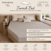 Bed met beige hoeslaken, drie kussens, houten hoofdeinde en plank met vaas en droogbloemen, raam met bomen en lucht, zichtbaar merklogo en tekstoverlays