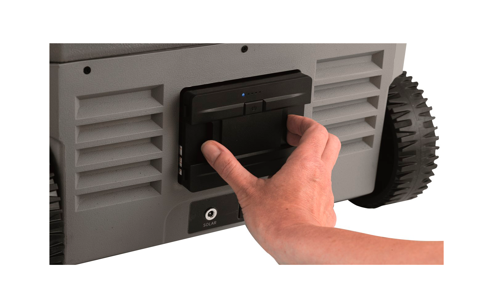 Hand schiebt einen schwarzen Hebel an einem grauen Gerät mit Lüftungsschlitzen und Rädern