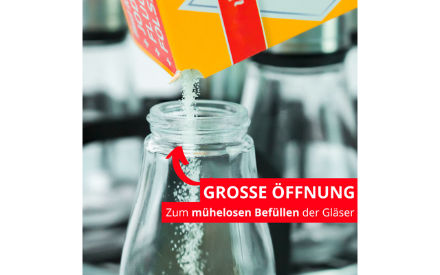 De la poudre est versée d'un carton jaune dans un bocal en verre ouvert ; une flèche rouge et une bande rouge avec le texte blanc 'GROSSE ÖFFNUNG Zum mühelosen Befüllen der Gläser'