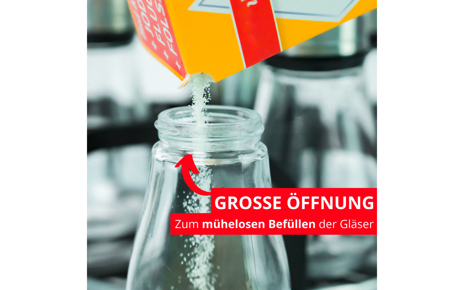 De la poudre est versée d'un carton jaune dans un bocal en verre ouvert ; une flèche rouge et une bande rouge avec le texte blanc 'GROSSE ÖFFNUNG Zum mühelosen Befüllen der Gläser'