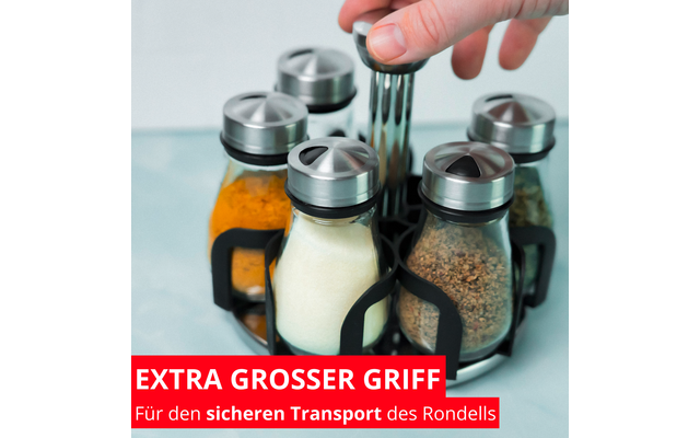 Main saisit un bocal en verre rond avec couvercle métallique dans un support noir; cinq bocaux en verre contenant des poudres colorées (jaune, blanc, brun, vert) sur fond bleu clair; bandeau rouge en bas avec texte blanc 'EXTRA GROSSER GRIFF Für den sicheren Transport des Rondells'