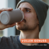 Nahaufnahme eines Mannes mit Strickmütze und Bart, der aus einem Thermobecher trinkt; orangefarbener Banner mit weißem Text 'VOLLER GENUSS' und kleinerem weißem Text 'frei von BPA und Blei'