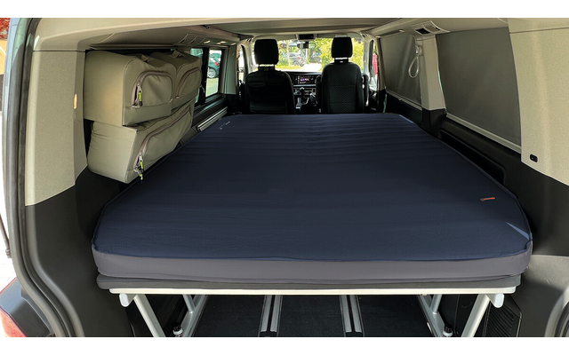 Vehicle interior with a dark blue mattress on a metal frame, two front seats and windows visible