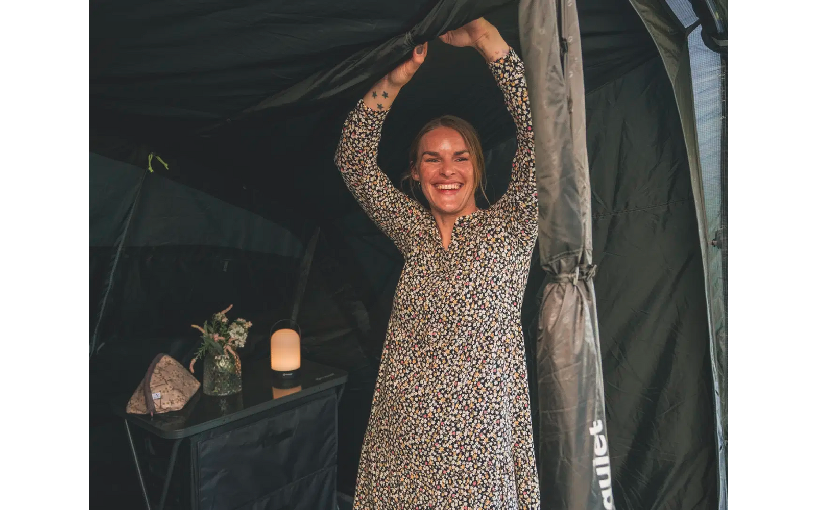 Frau in langem Kleid steht in einem Zelt und streckt die Arme nach oben