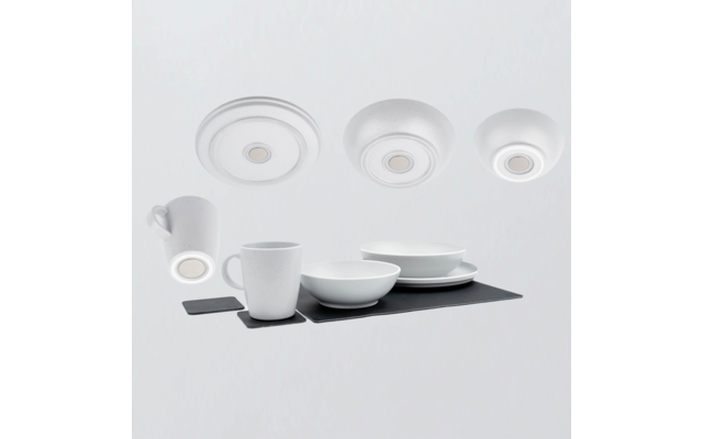 Vaisselle blanche sur un sous-plat rectangulaire foncé : deux tasses, deux bols, assiettes empilées ; trois disques ronds blancs en haut