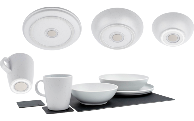 Weißes Geschirr auf dunklem rechteckigem Untersetzer: zwei Tassen, zwei Schalen, gestapelte Teller; drei runde weiße Scheiben oben