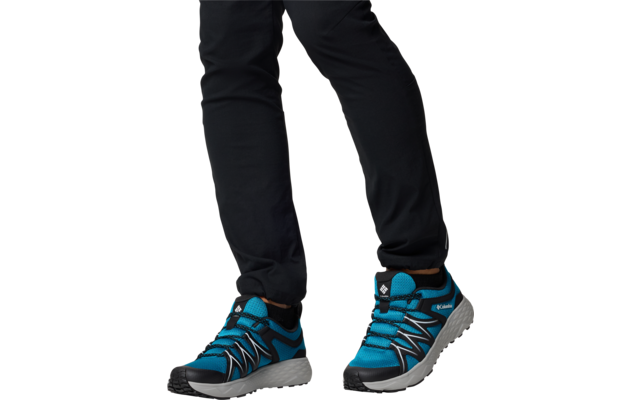 Jambes avec pantalon noir et chaussures de sport bleues sur fond blanc