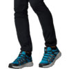Jambes avec pantalon noir et chaussures de sport bleues sur fond blanc