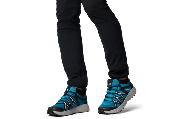 Beine mit schwarzen Hosen und blauen Sportschuhen auf weißem Hintergrund