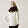 Person von hinten mit lockigem Haar, weißem Pullover und beiger Mütze