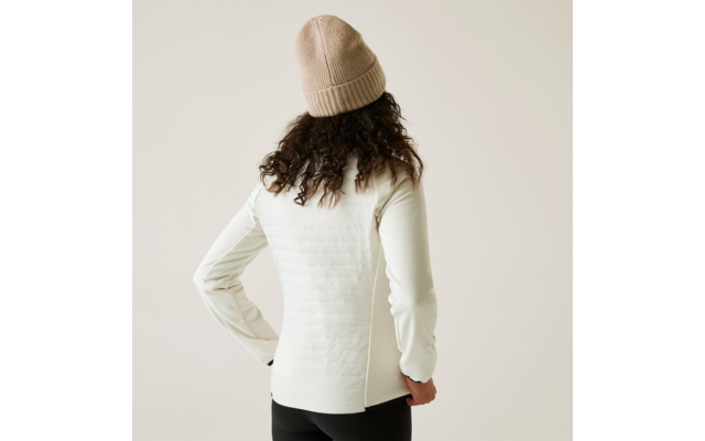 Person von hinten mit lockigem Haar, weißem Pullover und beiger Mütze