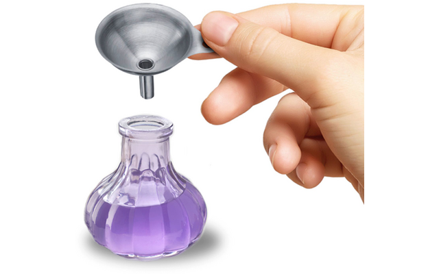 Main tenant un petit entonnoir métallique au‑dessus d'une petite bouteille en verre contenant un liquide violet