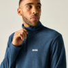 Oberkörper eines Mannes in blauem Fleece mit halbem Reißverschluss, Hand hält den Reißverschluss, er blickt zur Seite, heller Hintergrund